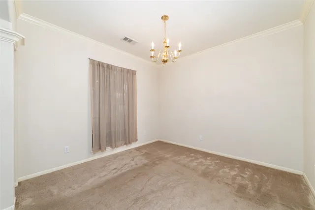 an empty room with a chandelier fan and windows