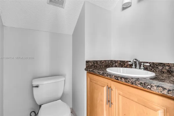 a bathroom with a granite countertop toilet sink and mirror