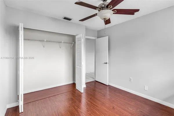 an empty room with wooden floor closet and fan