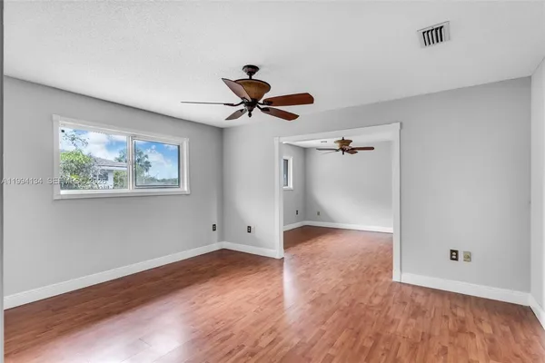 a view of wooden floor and a chandelier fan in a room