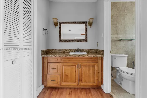 a bathroom with a granite countertop sink a toilet and a mirror
