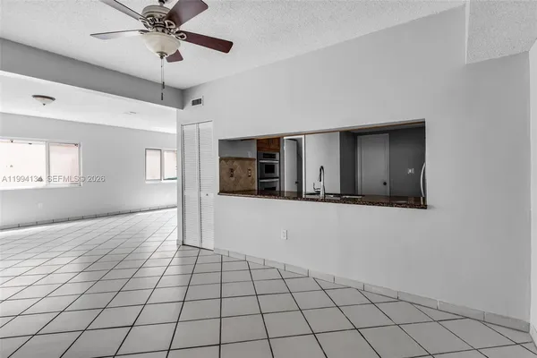 a view of an empty room with window and chandelier fan