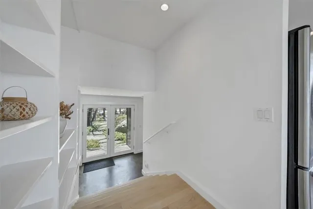 a view of hallway with window and wooden floor