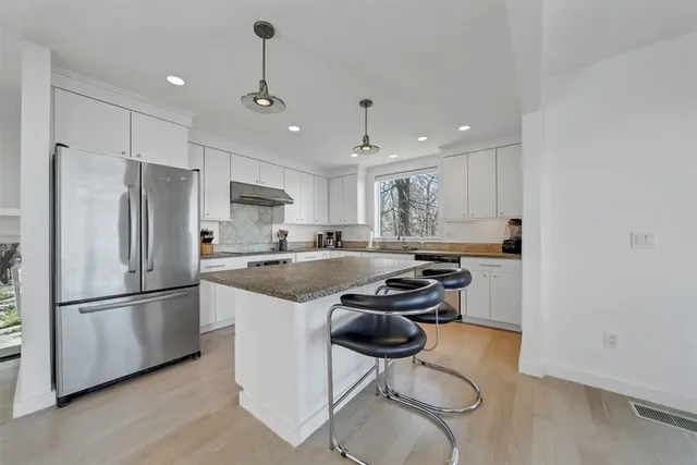 a kitchen with stainless steel appliances granite countertop a sink refrigerator and cabinets