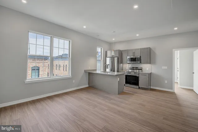 a large kitchen with a wooden floor and stainless steel appliances