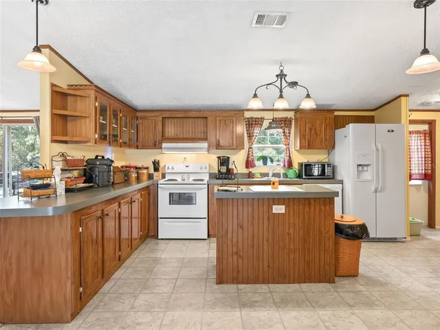 a kitchen with stainless steel appliances granite countertop a refrigerator a sink dishwasher a stove with wooden cabinets and a granite counter top