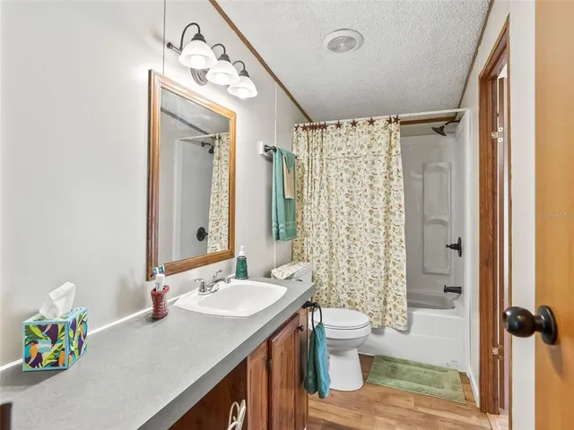 a bathroom with a granite countertop sink a toilet a mirror a vanity and shower
