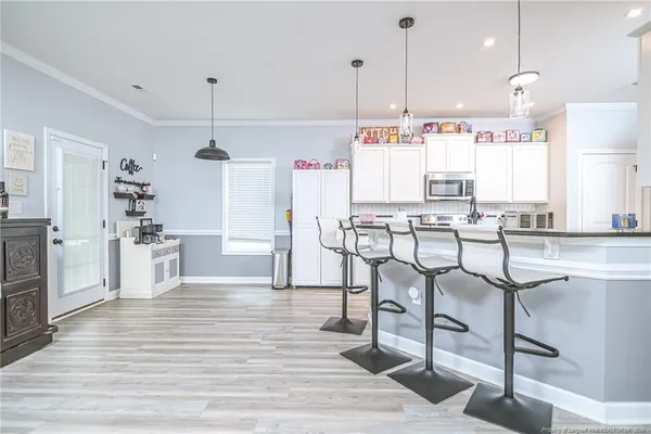 a kitchen with stainless steel appliances kitchen island granite countertop a table chairs stove and white cabinets