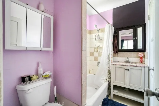 a bathroom with a granite countertop sink a toilet a mirror and bathtub