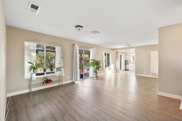 a view of an empty room with potted plants and wooden floor