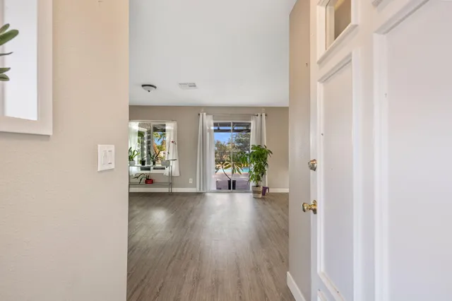 a view of an empty room with wooden floor and a window