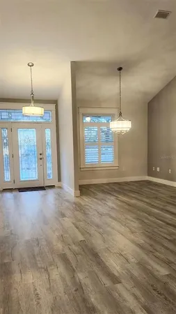 an empty room with wooden floor and chandelier