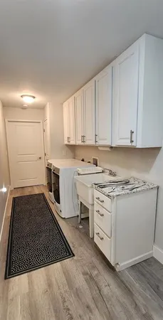 a kitchen with granite countertop a stove a sink and white cabinets