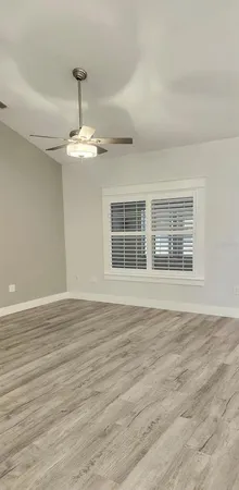 a view of an empty room with wooden floor fridge and a chandelier