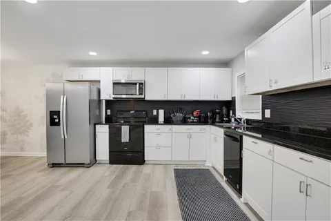 a kitchen with granite countertop white cabinets and stainless steel appliances