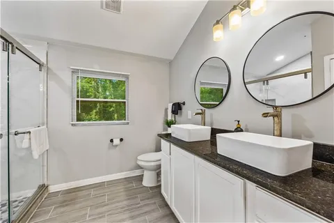 a bathroom with a granite countertop toilet a sink and a mirror