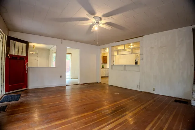 a view of an empty room with window and wooden floor