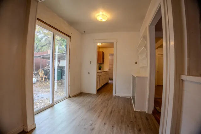 a view of a hallway with wooden floor and a bathroom