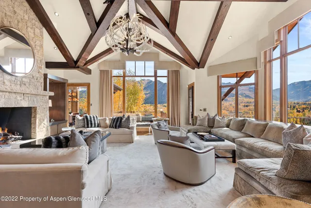 a living room with furniture a fireplace a large window and a chandelier