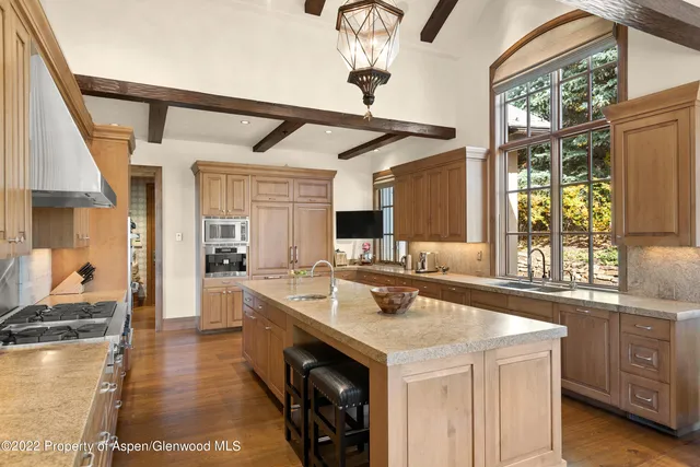 a large white kitchen with a sink and a large window
