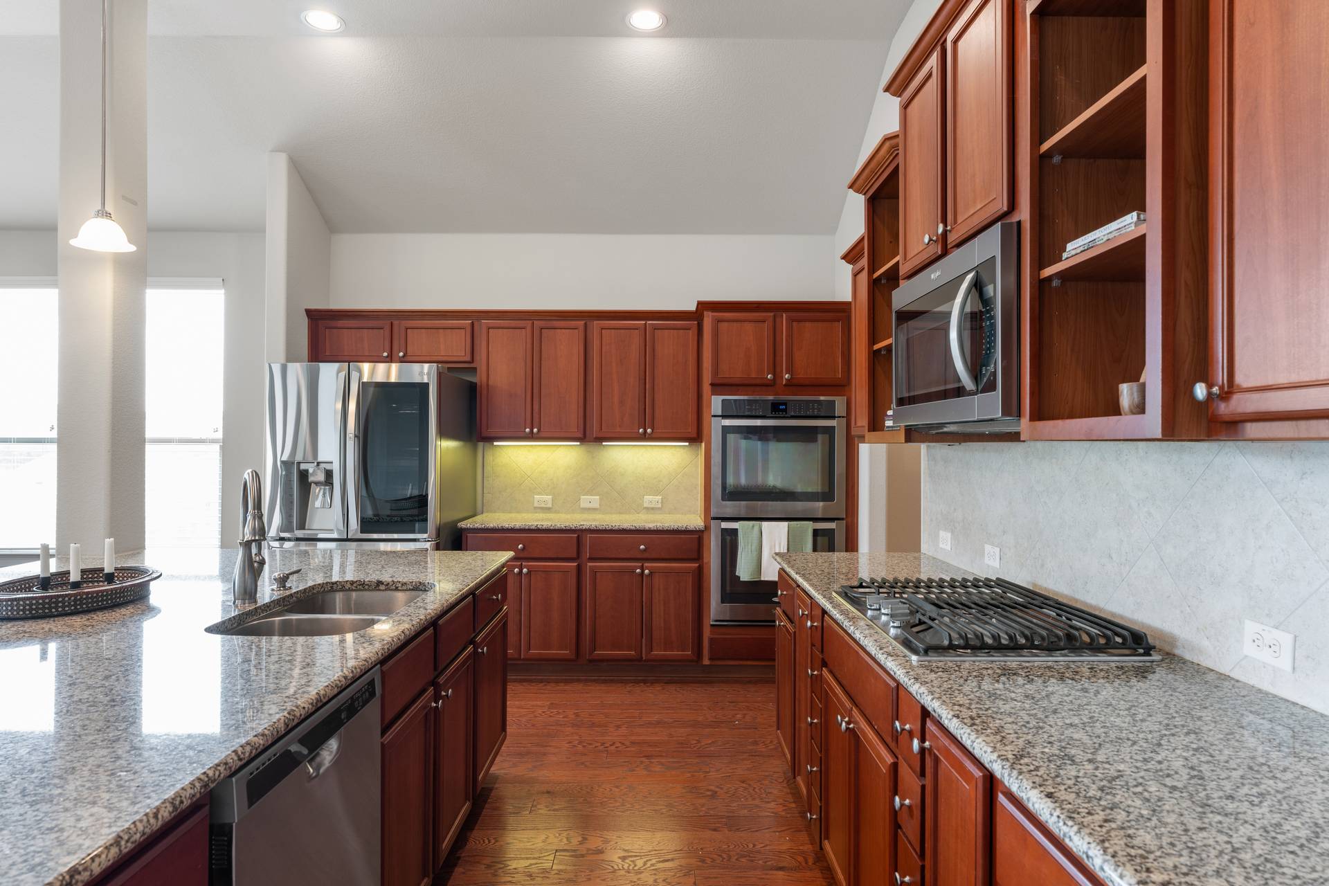 3516 Venezia View Leander, TX 78641 - Photo 6 of 40 Kitchen with stainless steel appliances, dark wood-type flooring, light stone counters, and backsplash
