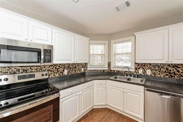 a kitchen with granite countertop a sink stove and cabinets