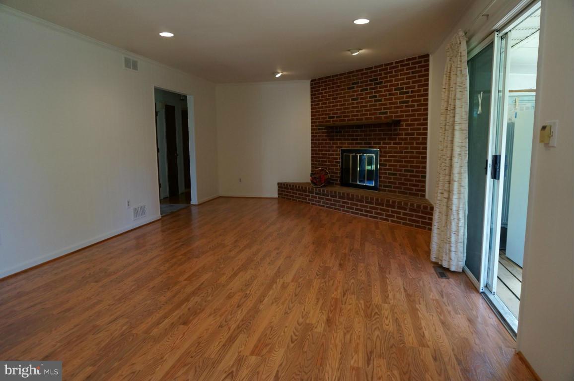 8611 McDaniel Road Baltimore, MD 21237 - Photo 3 of 21 an empty room with wooden floor and fireplace
