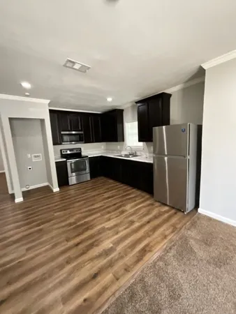a view of kitchen with stainless steel appliances wooden floor and living room