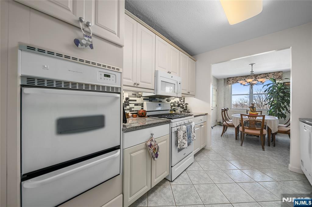 2200 North Central Road, Unit 6H Fort Lee, NJ 07024 - Photo 7 of 18 a kitchen with granite countertop white cabinets and white appliances