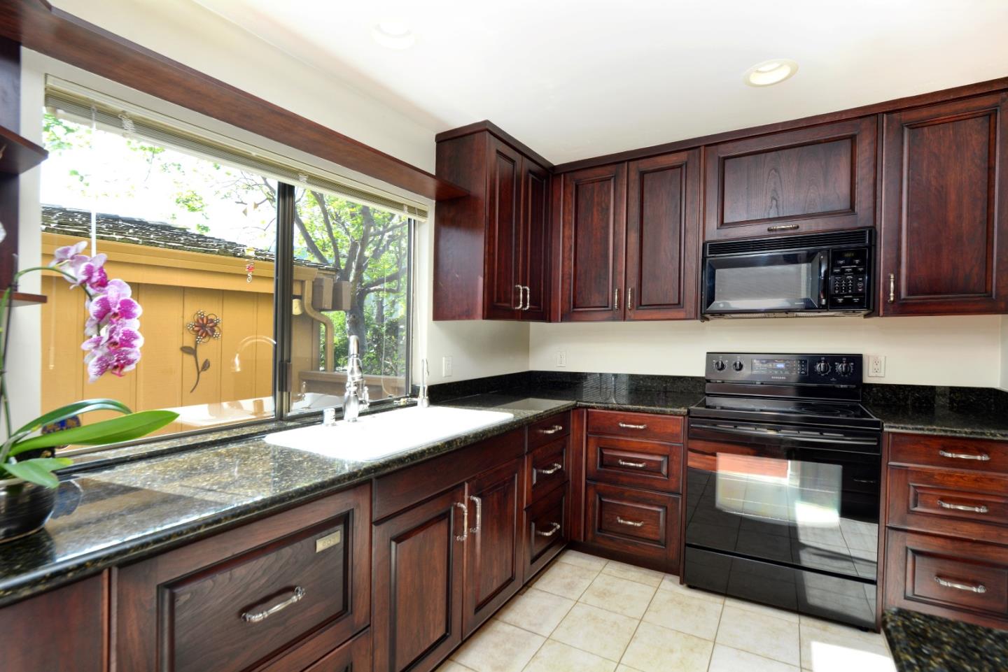3850 Rio Road, Unit 40 Carmel, CA 93923 - Photo 10 of 28 a kitchen with granite countertop wooden cabinets stainless steel appliances a large window and a sink