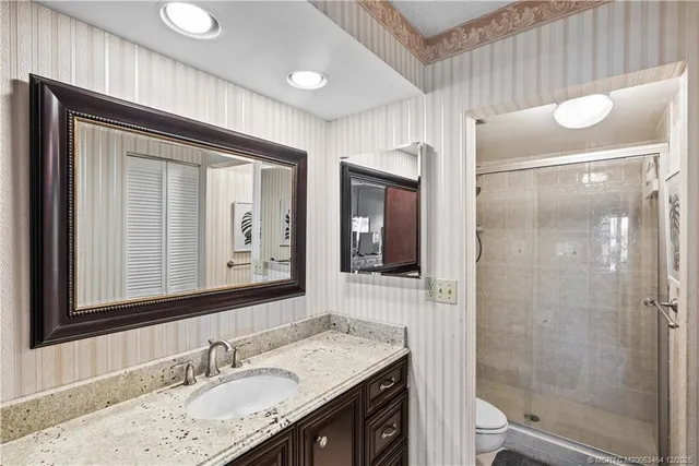 a bathroom with a granite countertop sink mirror and shower