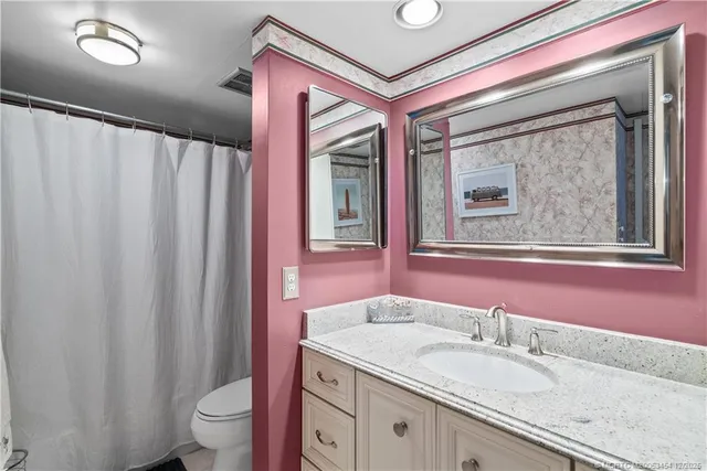 a bathroom with a granite countertop sink toilet and mirror