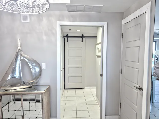 a view of a hallway with wooden floor and a large mirror
