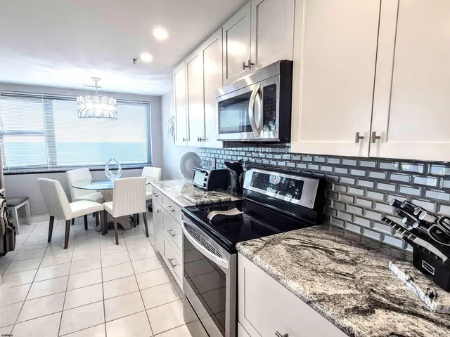 a kitchen with granite countertop a refrigerator and a stove top oven