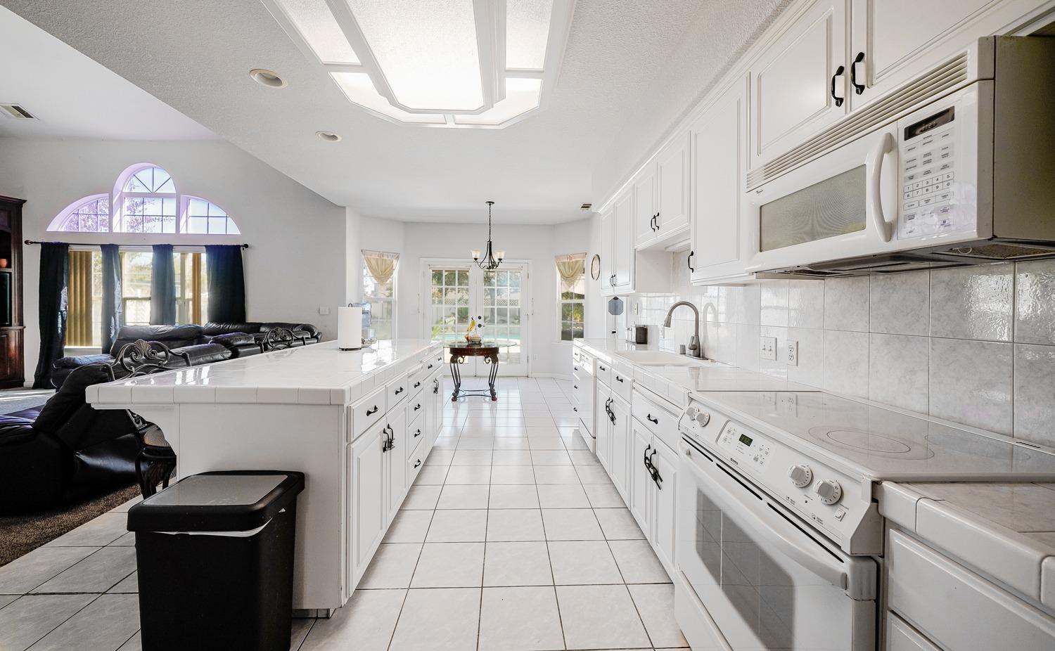 19360 Maple Street Laton, CA 93242 - Photo 4 of 53 a large white kitchen with a stove a sink a microwave and cabinets