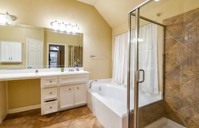 a spacious bathroom with a double vanity sink a mirror a bathtub and shower