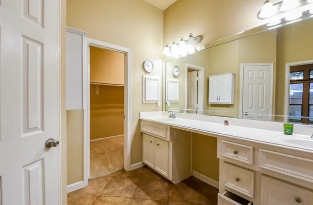 a spacious bathroom with a double vanity sink a mirror and a bathtub