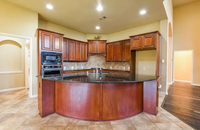 a kitchen with stainless steel appliances granite countertop a refrigerator a stove and a sink with wooden cabinets