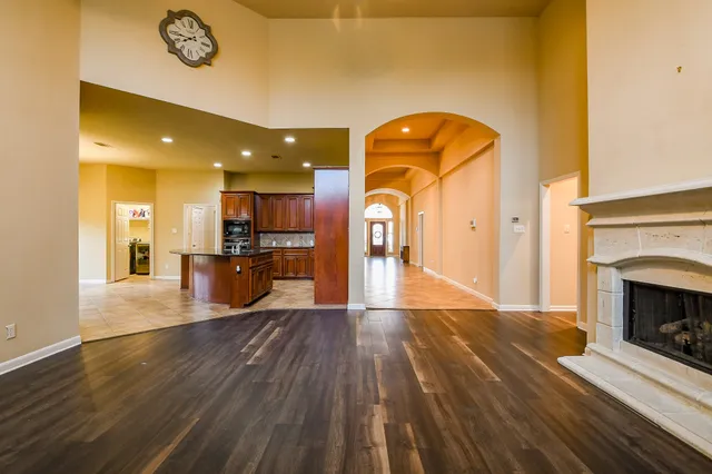 a view of a living room with wooden floor and a fireplace