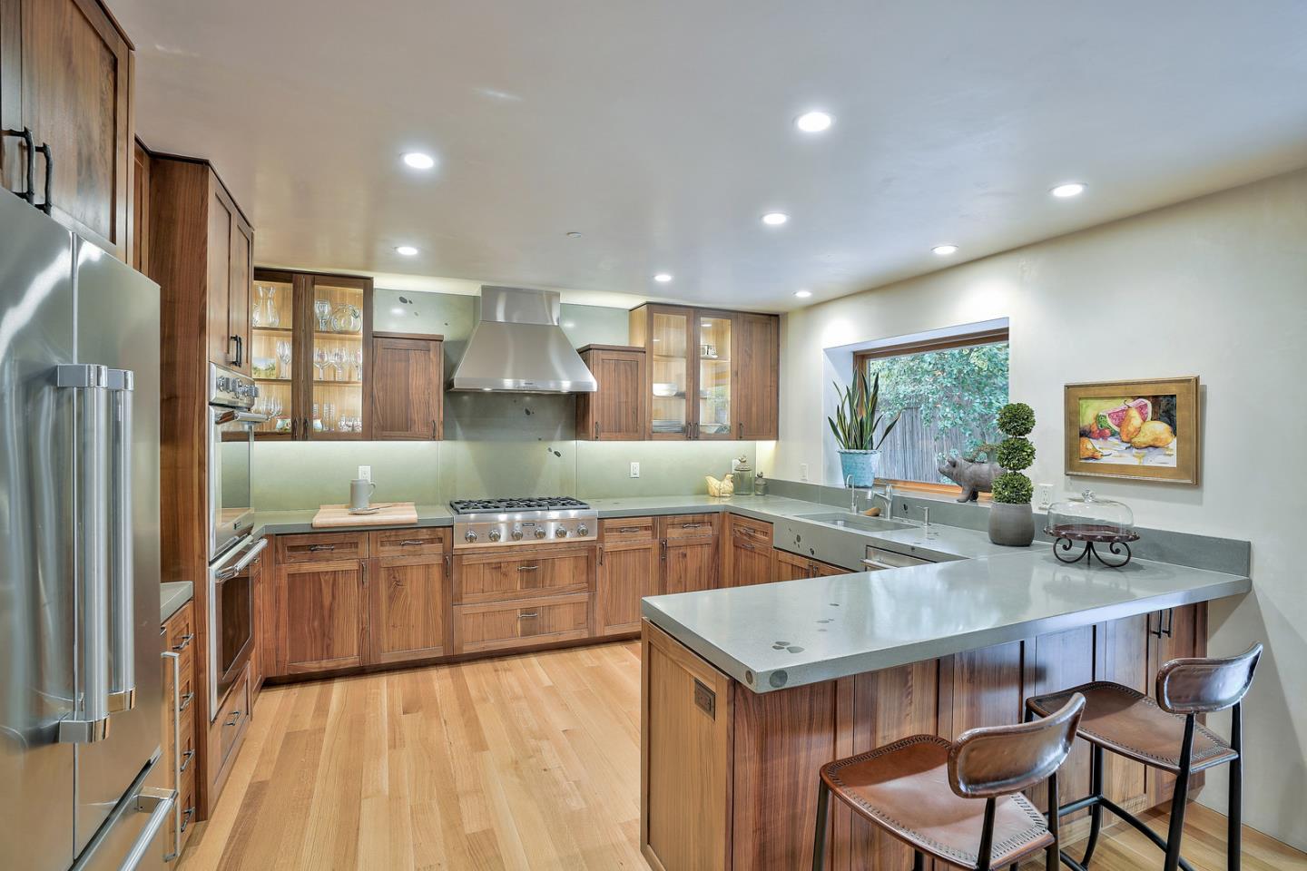 a kitchen with stainless steel appliances granite countertop a stove a refrigerator a kitchen island a table and chairs