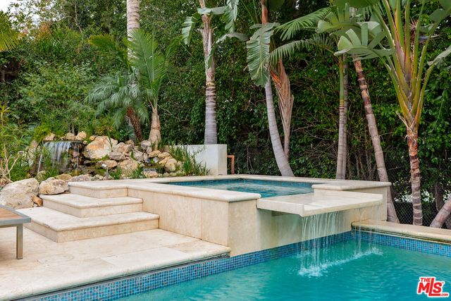 a view of a backyard with couches plants and large trees