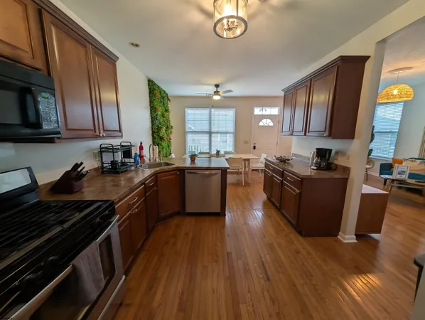 a kitchen with stainless steel appliances granite countertop wooden cabinets a sink dishwasher a stove and a refrigerator