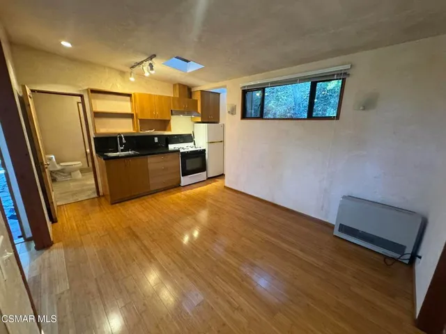 a large kitchen with a wooden floor and stainless steel appliances