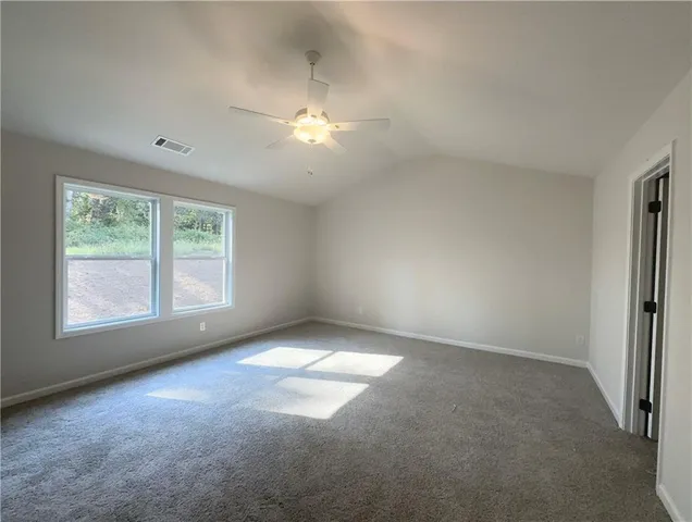 an empty room with a fan & a window