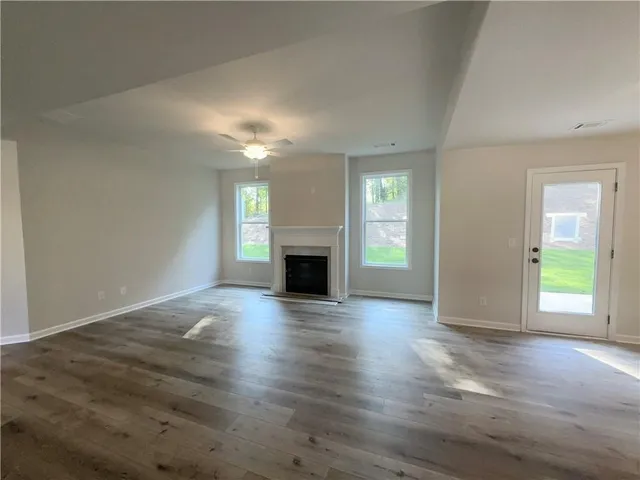 an empty room with wooden floor fireplace and windows