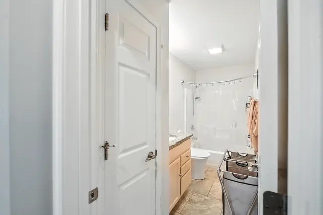 a bedroom with a bed a mirror on the dresser and a chandelier