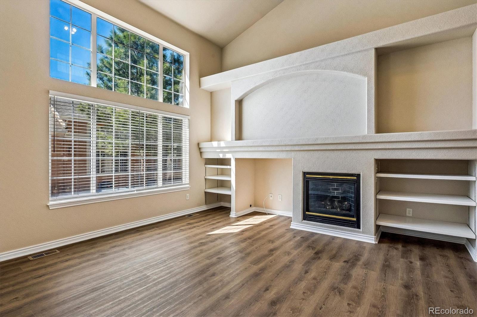 4545 South Taft Way Morrison, CO 80465 - Photo 5 of 19 an empty room with a fireplace cabinet and windows