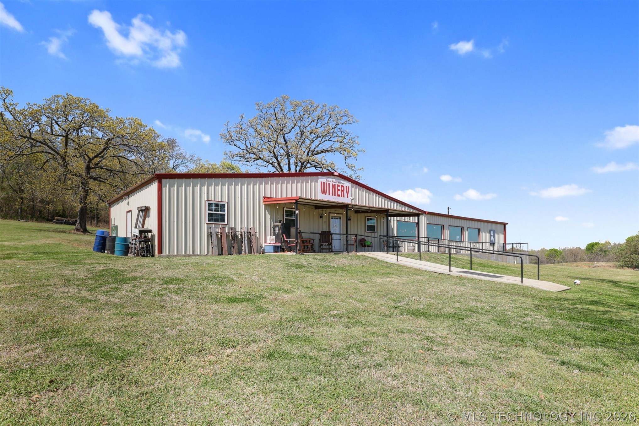 3565 Sawmill Road Caddo, OK 74729 - Photo 4 of 32 Metal-sided building with red trim, featuring a covered entry, an accessible ramp, and multiple windows