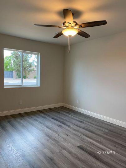 1136 West Boston Avenue Ridgecrest, CA 93555 - Photo 7 of 23 an empty room with wooden floor fan and windows