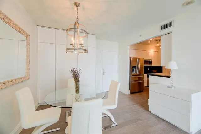 a dining room with furniture a chandelier and kitchen view